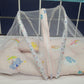 Baby crib with a pink mattress and colorful bear design against a blue tiled wall.