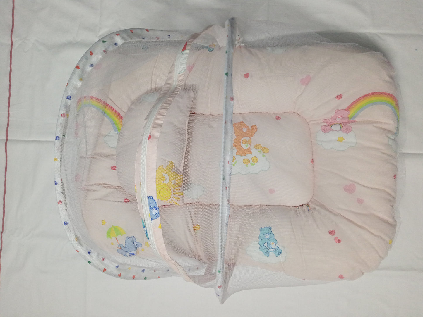 Baby crib with colorful bedding featuring cartoon characters on a white background