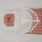 Red checkered fabric with a white circle and colorful dots on a light gray background