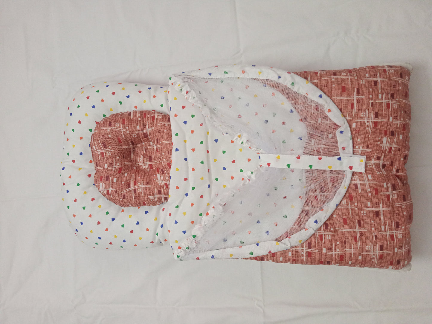 Red and white baby outfit with colorful polka dots on a light gray background